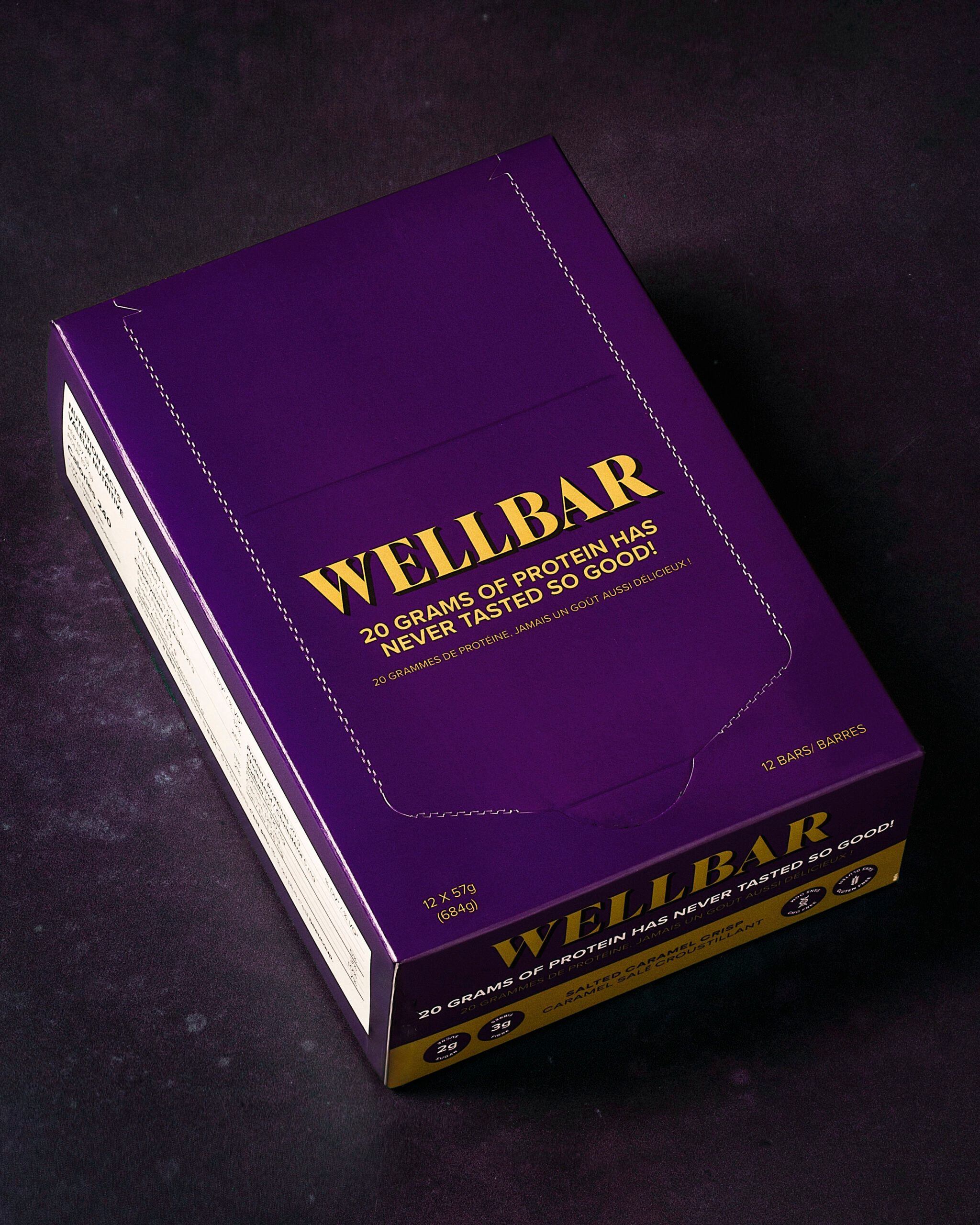 Wellbar High Protein Bar Box of 12, featuring a sleek purple box with yellow text, ideal for those seeking a tasty, nutritious snack option.