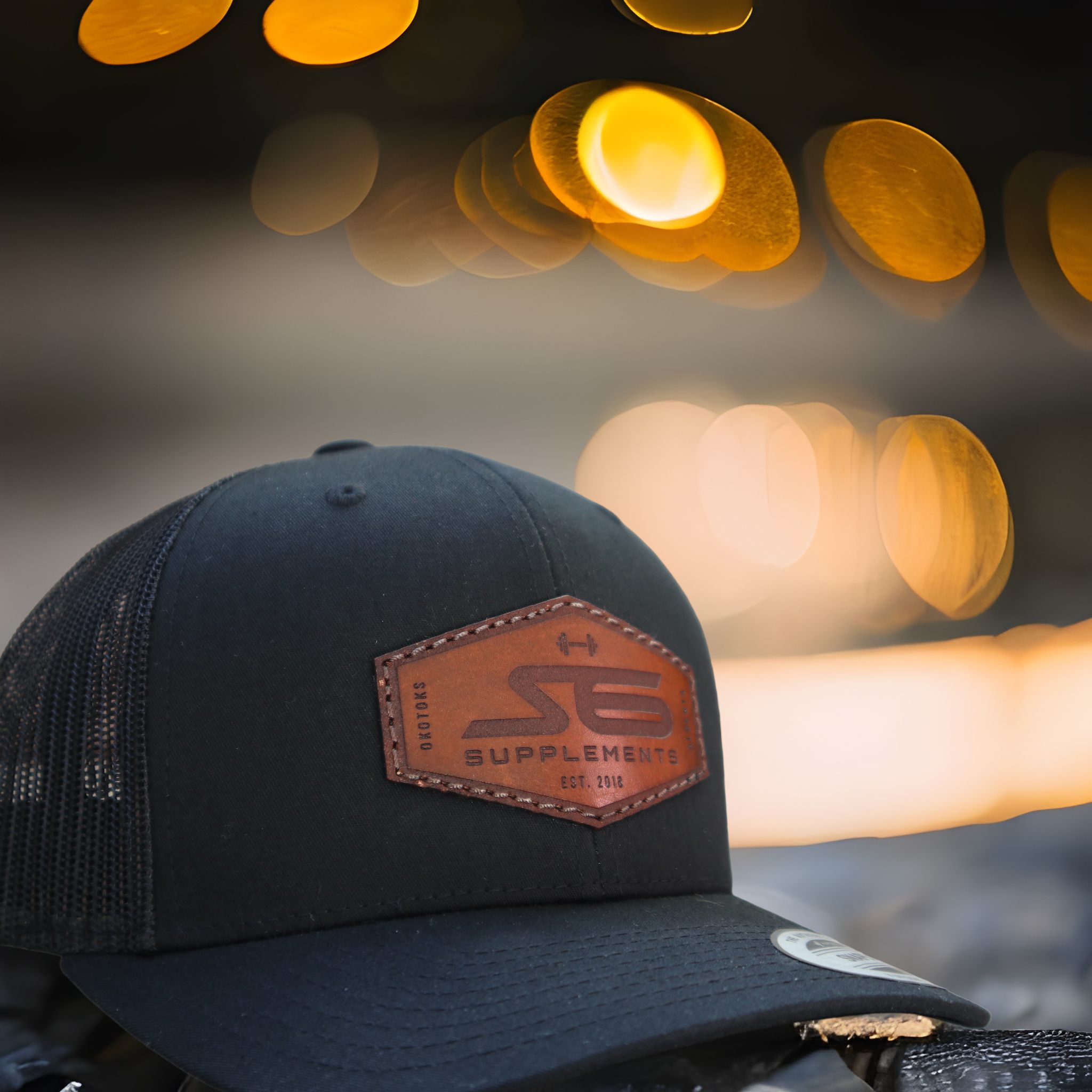 S6 Snap Back Leather Patch: A black cap featuring a brown leather S6 patch, hand-stitched and waxed, ideal for athletes and fitness enthusiasts.
