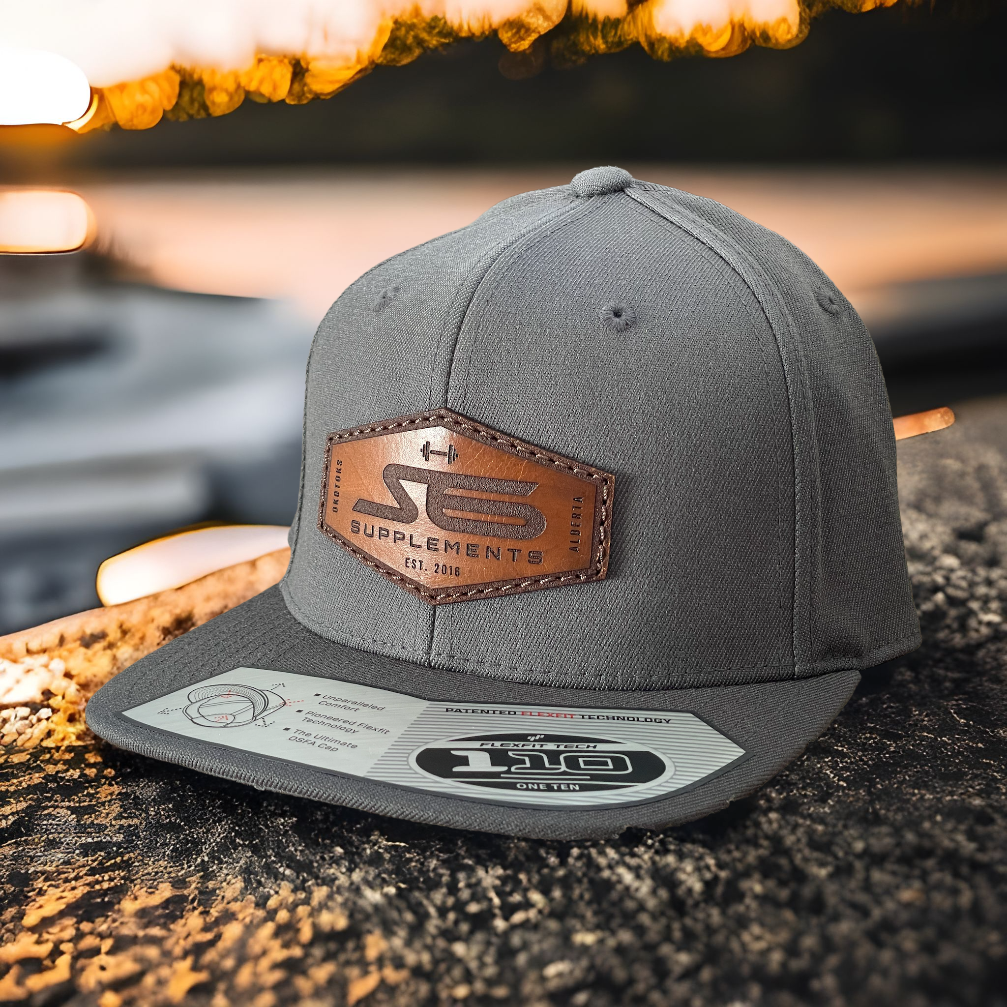 S6 Flat Brim Leather Patch Hat on a rock, featuring a brown leather label, ideal for outdoor and fitness enthusiasts.