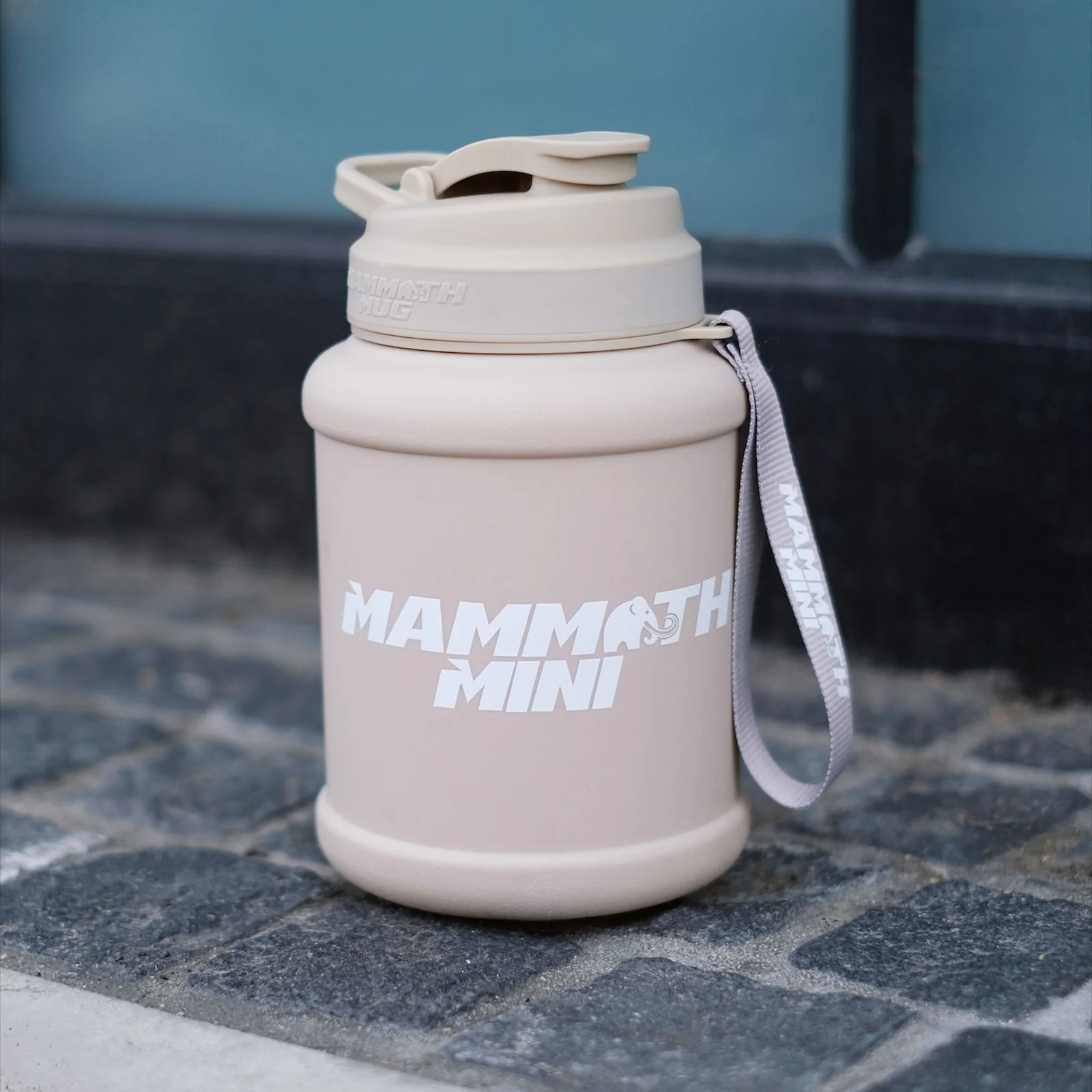 Mammoth Mug Mini 1.5L featuring a redesigned leak-proof lid, wrist lanyard, and engraved scale on the side, resting on a brick surface.
