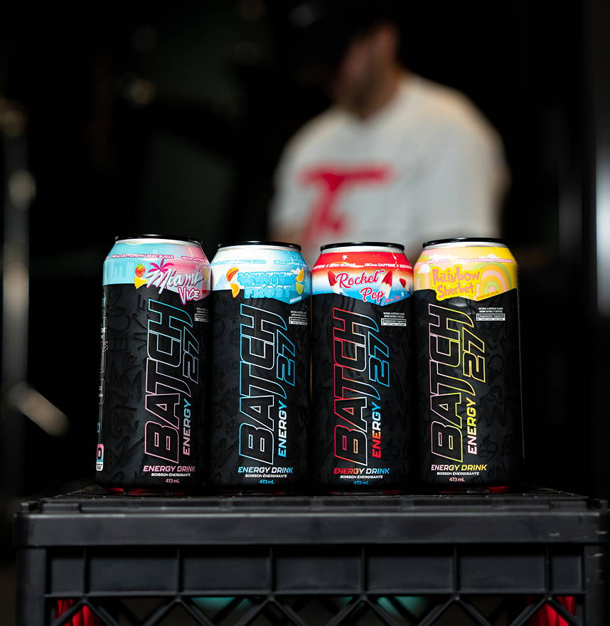 Batch 27 Energy Drink cans showcase four flavors on a crate, emphasizing their high-caffeine, zero-sugar formulation ideal for fitness enthusiasts.